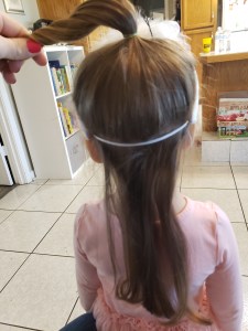 Divide hair and put the top half in a ponytail. Place headband on head with elastic on top of bottom half of hair.